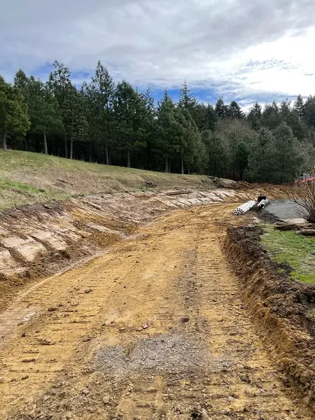 Driveway excavated into the hillside with drainage pipe ready to install