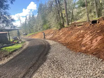 Curving gravel road beside a freshly cut hillside bank