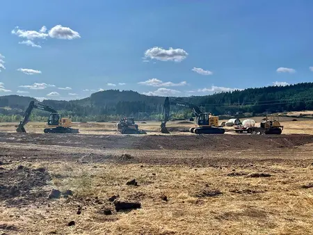 Two excavators, a track loader, and a dozer working the pond site