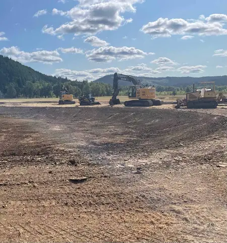 Graded pond bank with excavation equipment on the rim