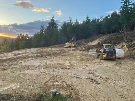 Excavator and track loader grading the shop pad at sunset