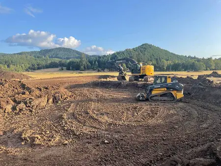 Excavator and track loader shaping the pond excavation